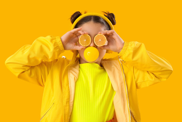 Funny girl with lemons blowing bubble gum on yellow background - Photo, Image