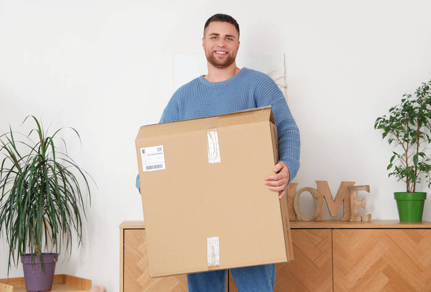 Молодой человек с большой коробкой посылок дома - Фото, изображение