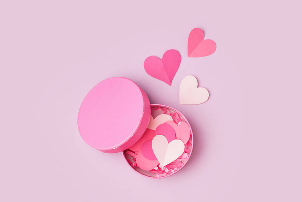 Scatola regalo con cuori di carta rosa su sfondo lilla. Festa di San Valentino - Foto, immagini