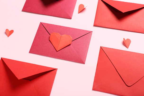 Composición con sobres y corazones de papel sobre fondo rosa. Celebración de San Valentín - Foto, Imagen