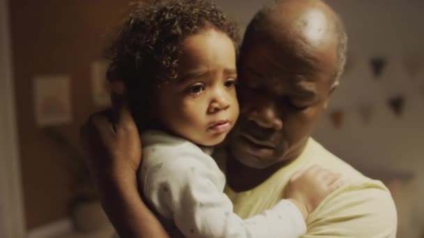 Close-up de pai afro-americano em pé no quarto segurando triste menina Biracial com lágrima e consolando-a a dormir à noite - Filmagem, Vídeo