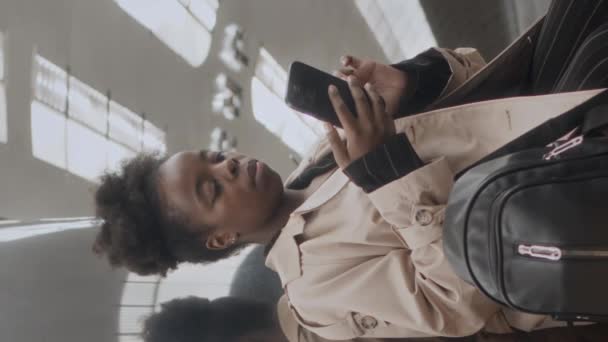 Függőleges közepes lövés a fiatal fekete nő áll a különböző oldalain rozsdamentes acél tükör oszlop metróállomáson, és várja a vonat - Felvétel, videó