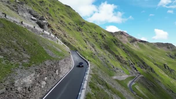 Стилфс, Италия - 30 июля 2023 года: голубой кабриолет Porsche 911 едет вверх по холму на дороге Стелфс по серпантину с панорамой горных Альп. Автомобиль является спортивным автомобилем производства Porsche. - Кадры, видео