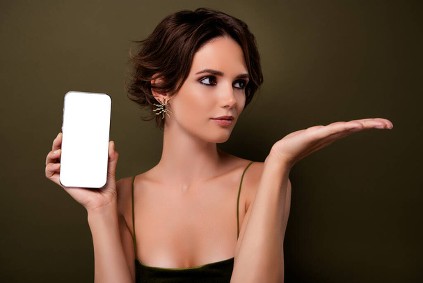 Фото привлекательной девушки держать сотовый смартфон рука продемонстрировать зеленый цвет пустое пространство фона для рекламы. - Фото, изображение