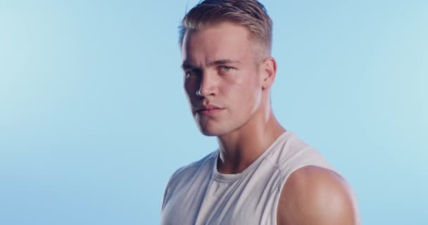 Fitness, serious man and face with confidence from workout, exercise and training in studio. Strong muscle, portrait and male athlete with gym and sport health with blue background and wellness. - Footage, Video