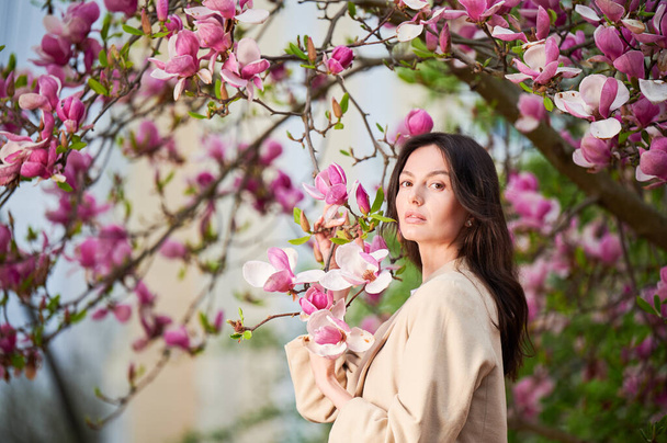 Kobieta uczulona ciesząca się po leczeniu sezonowej alergii wiosną. Portret szczęśliwej młodej kobiety przed kwitnącym drzewem magnolii wiosną. Wiosenna koncepcja alergii. - Zdjęcie, obraz