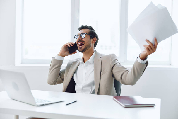 Férfi dokumentum iroda internet üzletember számítógép professzionális portré telefon laptop dolgozó munkás beszélgetés ül beszélgetés boldog vonzó nyertes férfi hívás mosoly mobiltelefon - Fotó, kép