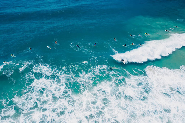 Surffaajat sinisessä valtameressä surffilaudalla ja aalloissa. Antenninäköala - Valokuva, kuva
