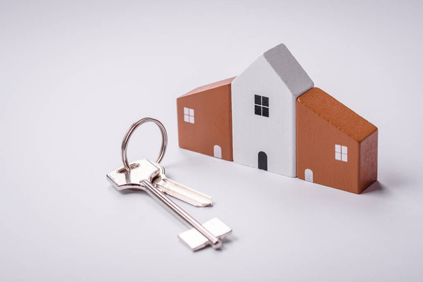 Een klein houten huis en sleutels als idee om te investeren in uw eigen huis en het doel van het kopen van onroerend goed te bereiken. Achtergrond voor uw idee - Foto, afbeelding