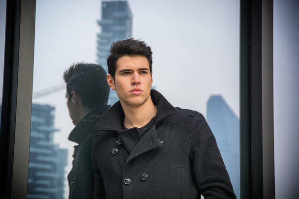 Young man standing outdoor against office window - Valokuva, kuva