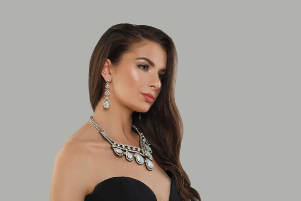 Modelo de jóias mulher glamourosa agradável com diamantes posando em fundo cinza - Foto, Imagem
