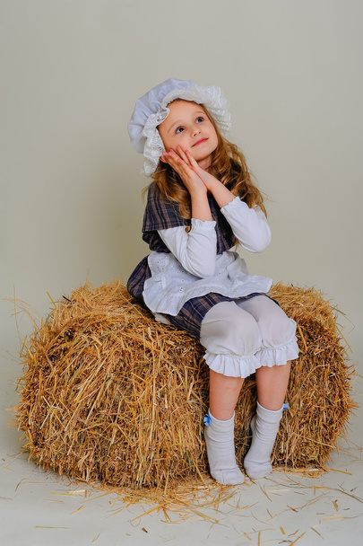 Girl in dress sitting on a rustic vintage straw bale - Foto, afbeelding