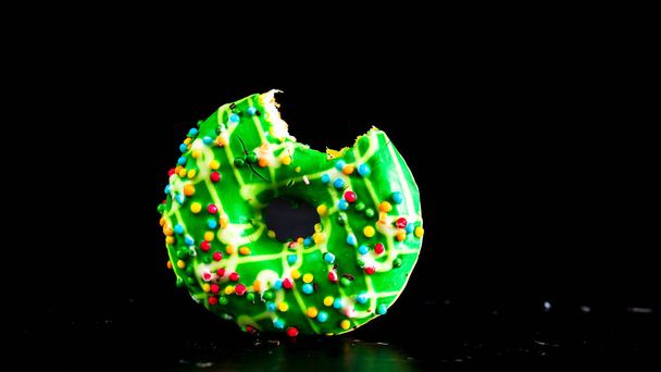 Green glazed donut with sprinkles isolated. Close up of colorful bitten donut. - Photo, Image