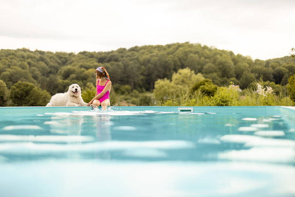 Kobieta odpoczywa ze swoim słodkim psem w pobliżu basenu, spędzając razem lato. Pojęcie przyjaźni ze zwierzętami domowymi i wakacji letnich - Zdjęcie, obraz