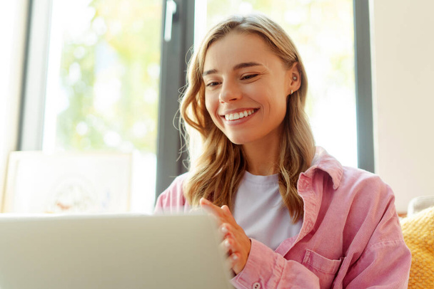 笑顔の魅力的な女性は,オンラインラップトップコンピュータ通信を使用して,ビデオ通話を持っています. 自宅で働く幸せなフリーランサー  - 写真・画像