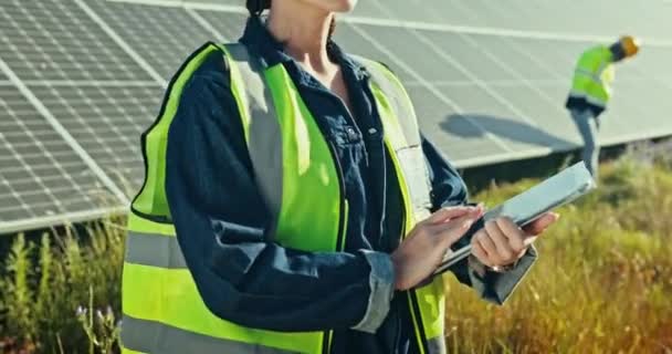 Woman at solar panel farm with tablet for clean energy, outdoor electricity grid maintenance and check. Sustainability, photovoltaic power system and technician with helmet for safety inspection - Footage, Video