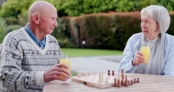Saft, Ruhestand und ein altes Paar, das gemeinsam im Garten ihres Seniorenheims Schach spielt, um sich zu entspannen. Liebe, Denken oder Strategie mit einem älteren Mann und einer älteren Frau auf dem Hof für ein Brettspiel. - Filmmaterial, Video