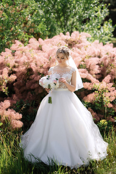 Bahar ormanında, düğün gününde beyaz elbiseli genç bir kız. - Fotoğraf, Görsel