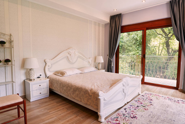 Велике двоспальне ліжко з тумбочками в кімнаті з панорамними вікнами. Високоякісна фотографія - Фото, зображення