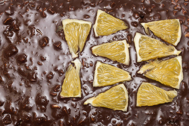Top view of orange segments arranged in triangular shapes on the chocolate and almond texture of a cocoa cake. Texture and flavors. - Photo, Image
