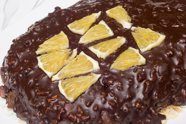 Extrême gros plan de segments orange triangulaires sur la texture chocolat et amande d'un gâteau au cacao. Texture et saveurs. - Photo, image