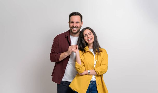 Portrait of loving young boyfriend and girlfriend holding hands and posing over white background - Photo, Image