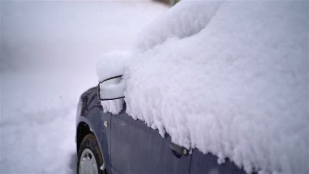 Nieve nevando sobre el coche aparcado en el fondo de la calle nevada en la estación fría de invierno en tormenta de nieve. Movimiento lento.  - Metraje, vídeo