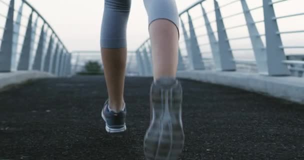 Vrouw, hardlopen en voeten op de brug voor marathon, training en oefening uitdaging in de stad in de sport wellness. Persoon, sterke atleet en inzet voor natuurlijke fitness en cardiotraining in de buitenlucht. - Video