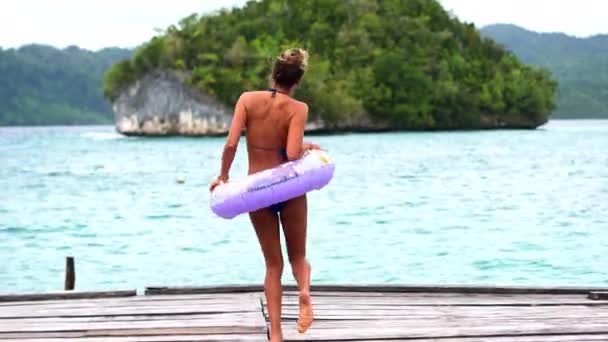 Kobieta, tańcząca przy plaży i pływająca pierścień, ciesząca się w bikini, ośrodku i strojach kąpielowych na letnie wakacje. Natura, czas wolny i szczęśliwy na wakacje, opalenizna i morze w plenerze, indonezji i oceanu. - Materiał filmowy, wideo