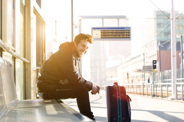 heureux jeune homme attendant le train à la gare avec sac - Photo, image