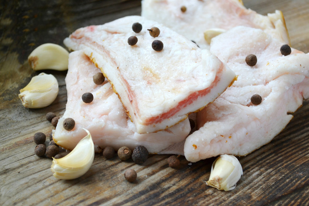 weißes Schweinefett namens salo mit Knoblauch und Pfeffer auf einem hölzernen Küchentisch - Foto, Bild