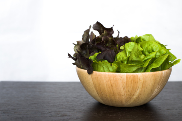 Twee (2) Toon salade in houten kom op donkere houten tafel geïsoleerd op - Foto, afbeelding