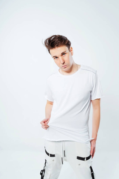 a photo shoot of a Russian guy on a white background. A Russian model poses in a fashionable summer T-shirt. photo shoot of youth clothes with a model in a photo studio - Photo, Image