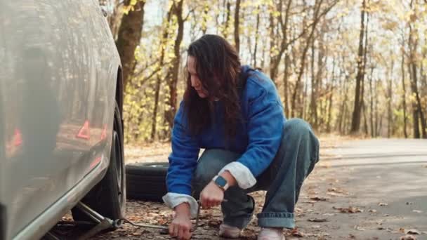Automotive Ordeal Unveiled : The Frustration and Triumph of a Determined Girl Managing Car Troubles, Executing a Tire Change in the Enchantting Forest. Images 4k de haute qualité - Séquence, vidéo
