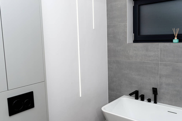 В современной ванной комнате в стене смонтированы легкие полоски, видна ванна. - Фото, изображение