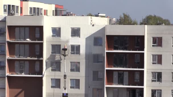 Arbeiter am Speziallift streicht neue flache Häuserwände - Filmmaterial, Video
