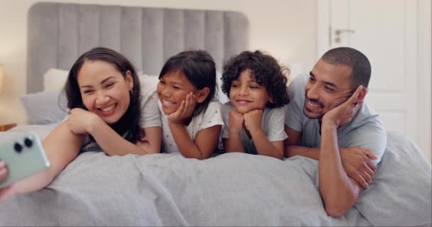Selfie, liefde en gelukkig gezin in een bed ontspannen, verbinden en glimlachen voor het geheugen in hun huis samen. Smartphone, profielfoto en kinderen met ouders in een hotelkamer met app voor fotografie. - Video