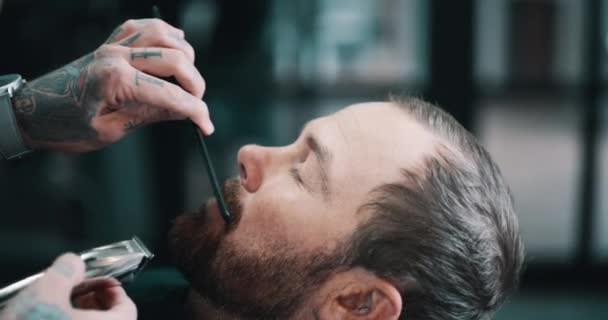 Face, beard or shave with a barber and man in a seat as a customer for luxury or professional service. Hands, salon or grooming and a person shaving the face of a client with an electric razor. - Footage, Video