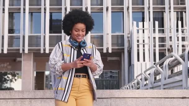 millennial afro woman talking in her phone and laughing outdoors. High quality FullHD footage - Footage, Video