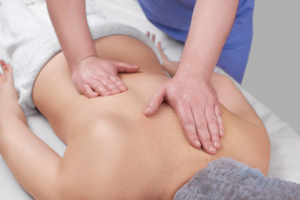 Масажист робить розслабляючий масаж на шиї, плечах і спині молодої красивої жінки в спа-салоні. Концепція косметології та масажу. - Фото, зображення