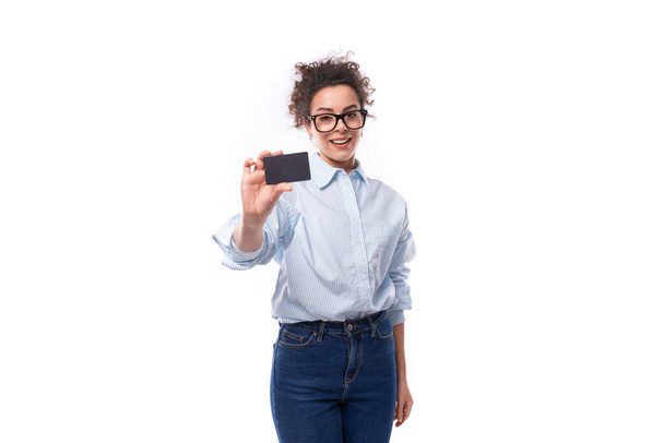 young successful confident leader woman with curly black hair in an office elegant shirt holds a credit plastic card mockup. e-business concept. - Photo, Image