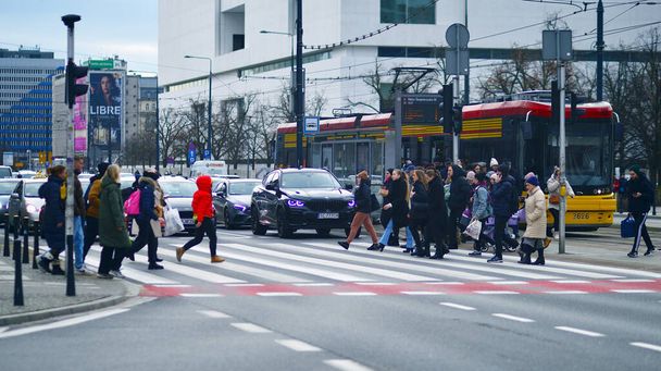 Βαρσοβία, Πολωνία. 29 Δεκεμβρίου 2023. Πλήθος ανθρώπων που διασχίζουν το δρόμο με φανάρι ζέβρα στην πόλη σε ώρα αιχμής. Τρόπος ζωής σε μια μεγάλη πόλη στην Ευρώπη. - Φωτογραφία, εικόνα