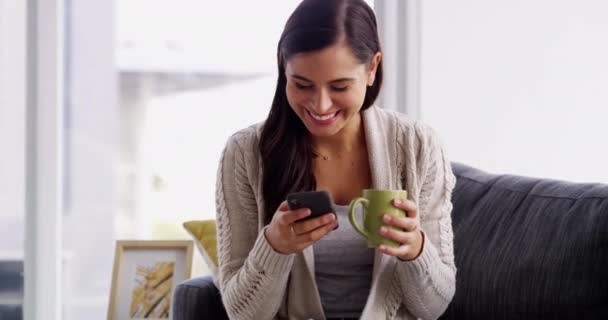 Kahve, kahkaha ve telefonlu mutlu kadın evde mesajlaşmak, sohbet etmek ya da iletişim kurmak için kanepede oturuyor. Oturma odasında sosyal medya, mim veya blog, gönderi veya komik gif ile akıllı telefon, uygulama ve kadın kişi. - Video, Çekim