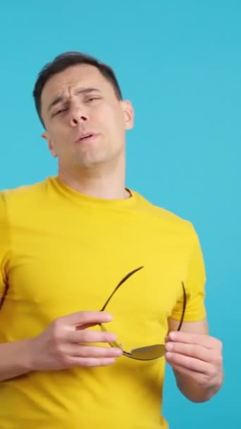 Video in studio met blauwe achtergrond van een pooier man zetten op zijn zonnebril - Video