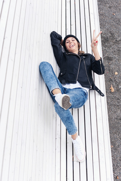 Beautiful young female lying on a park bench - 写真・画像