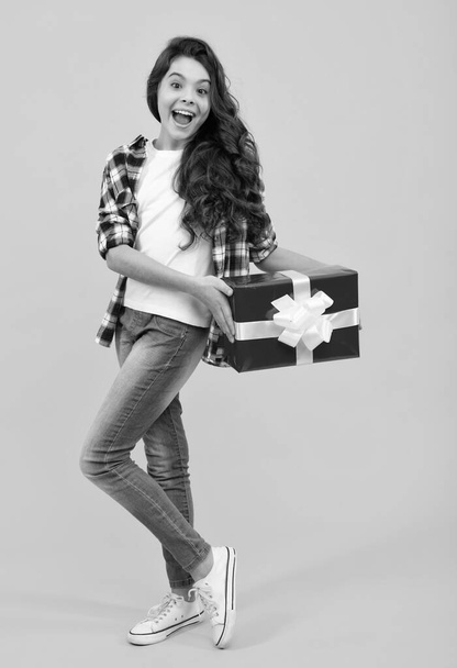 Happy teenager, positive and smiling emotions of teen girl. Child with gift present box on isolated studio background. Gifting for kids birthday - 写真・画像