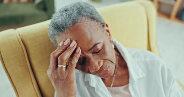 Stress, Kopfschmerzen und traurige ältere schwarze Frau in einem Stuhl mit Gedächtnis oder Depression im Pflegeheim. Angst, Gesicht und ältere afrikanische Dame im Wohnzimmer mit Demenz, Alzheimer oder Schwindel. - Filmmaterial, Video