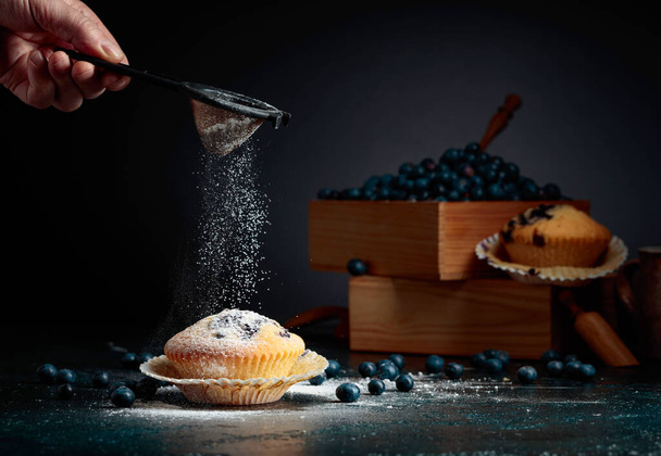 Blueberry muffins and berries in a wooden box. Muffins sprinkled with sugar powder. - Photo, Image