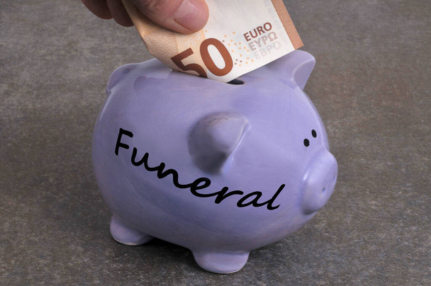 Bestattungskonzept: Jemand steckt einen Fünfzig-Euro-Schein in ein Sparschwein - Foto, Bild