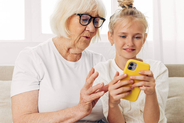 Видеопространство семейный телефон связи улыбающаяся копия в помещении образование белый звонок люди селфи фотографии футболка бабушка два ребенка обнимает внучка вместе диван - Фото, изображение
